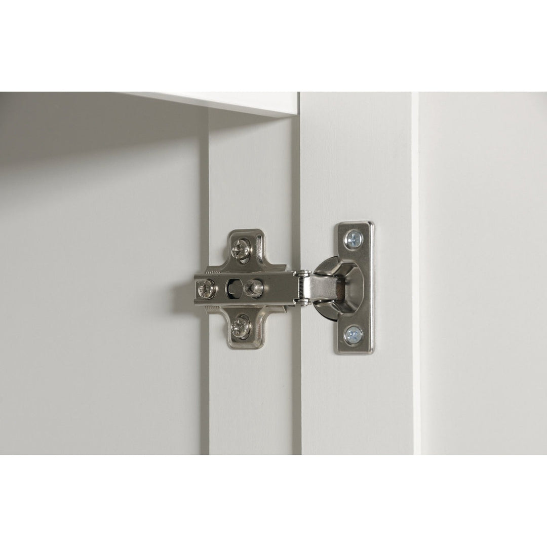 Close-up of a cabinet hinge on a white door