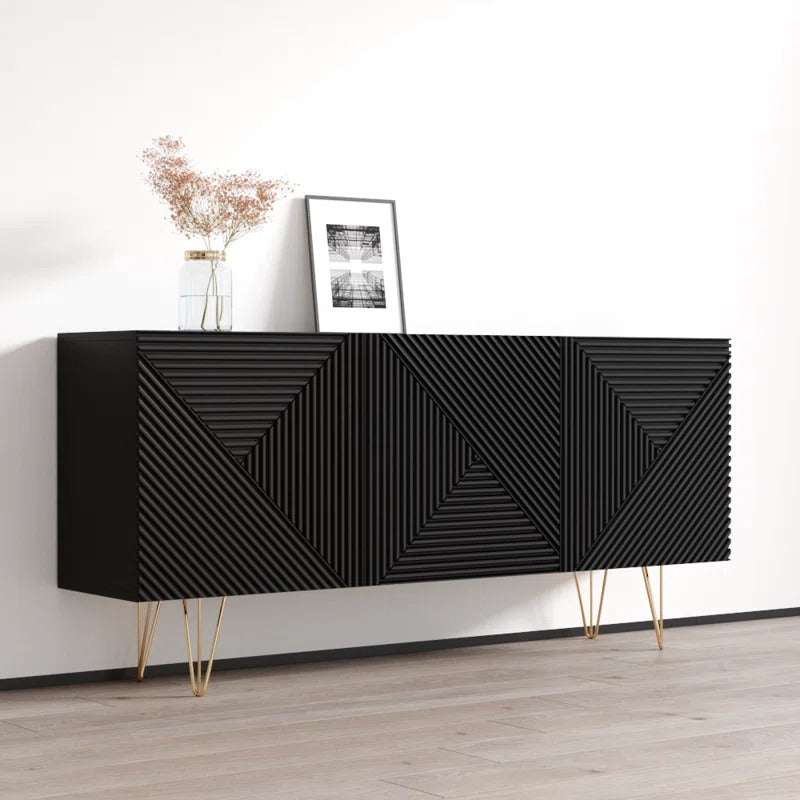 A modern black sideboard with geometric patterns, featuring golden details and stands on a wooden floor against a white wall with a small decorative item on top.