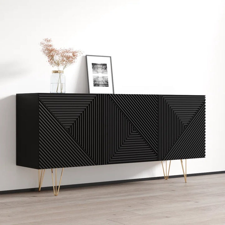 A modern black sideboard with geometric patterns, featuring golden details and stands on a wooden floor against a white wall with a small decorative item on top.