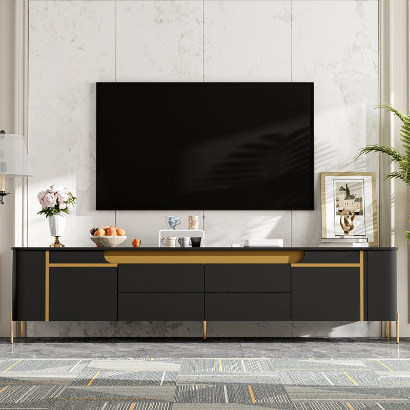 Modern black TV stand with gold accents, featuring multiple storage drawers and shutters, with a flat-screen TV on top.