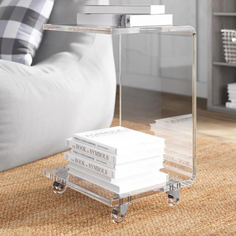 A clear acrylic C-shaped end table with a rectangular top, equipped with wheels.