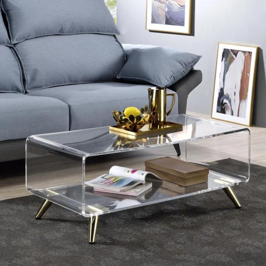 Clear Mosaic acrylic coffee table with waterfall-edge, two-tier design and angled gold metal legs in a modern living room