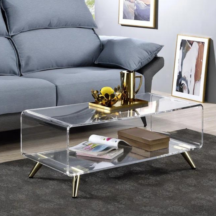Clear Mosaic acrylic coffee table with waterfall-edge, two-tier design and angled gold metal legs in a modern living room