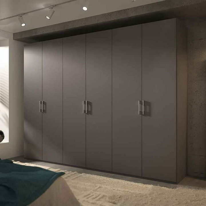 A matte black 6-door wardrobe with sleek silver handles installed in a room with a concrete wall.