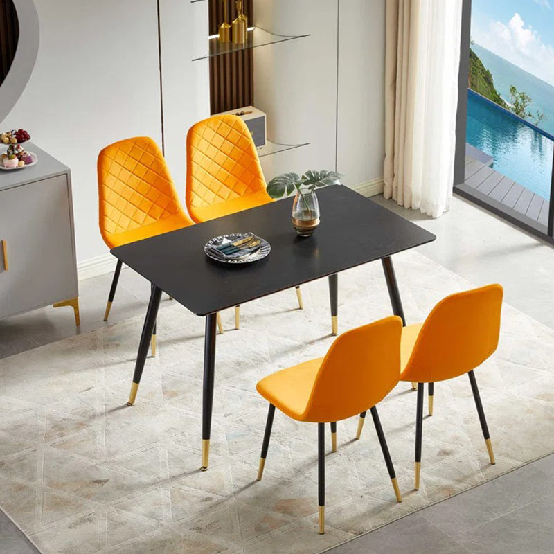 The modern black dining table is supported by four sturdy metal legs and 4 dining chairs in orange premium fabric