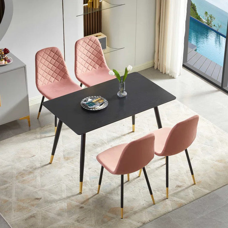A set of four pink upholstered dining chairs with black metal legs around a square dining table, placed on a rug in a room with a pool view.