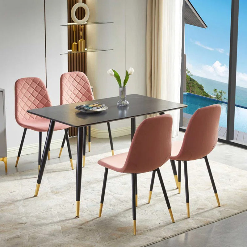 The sleek dining table is supported by four metal legs and 4 stylish chairs with black and gold legs. 