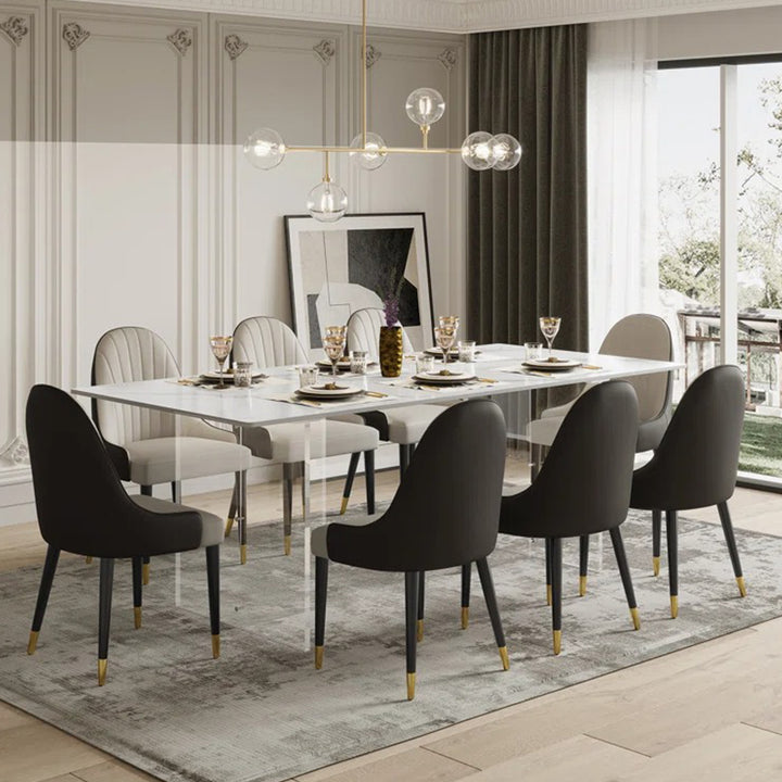 An 8-seater dining table set with a rectangular tabletop made of satvario stone plyboard, acrylic, and flexible ply, accompanied by four chairs with a similar design in a modern dining room.