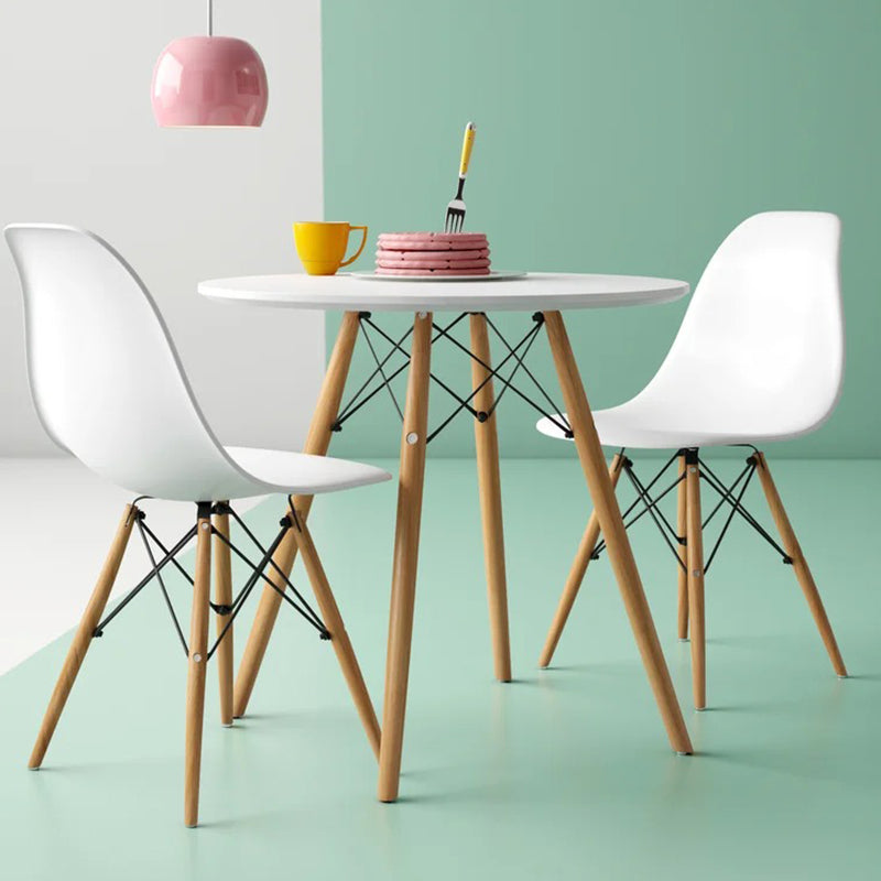 A modern dining set with a round white table and four white chairs with a space-saving design, featuring a two-tone finish with brown legs.