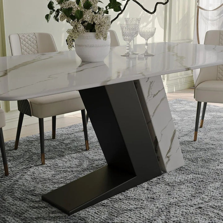 Modern dining table with a marble-like surface and modern design in a room with chairs and a rug.