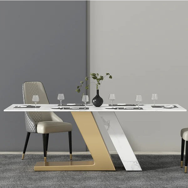 An 8-seater dining table set with a white Satarvio marble tabletop, gold-colored metallic legs, and gray upholstered chairs positioned in a modern dining room setting.
