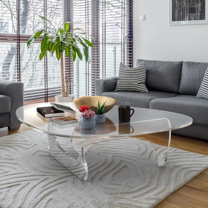Transparent Aurora acrylic table styled next to sofa, blending modern design with functional elegance in an airy living space.