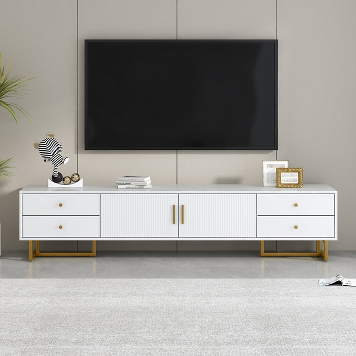A large white TV stand with a wave-groove pattern and metal frame, featuring multiple storage drawers and a cabinet, with a flat-screen TV on top and decorative items on the stand.