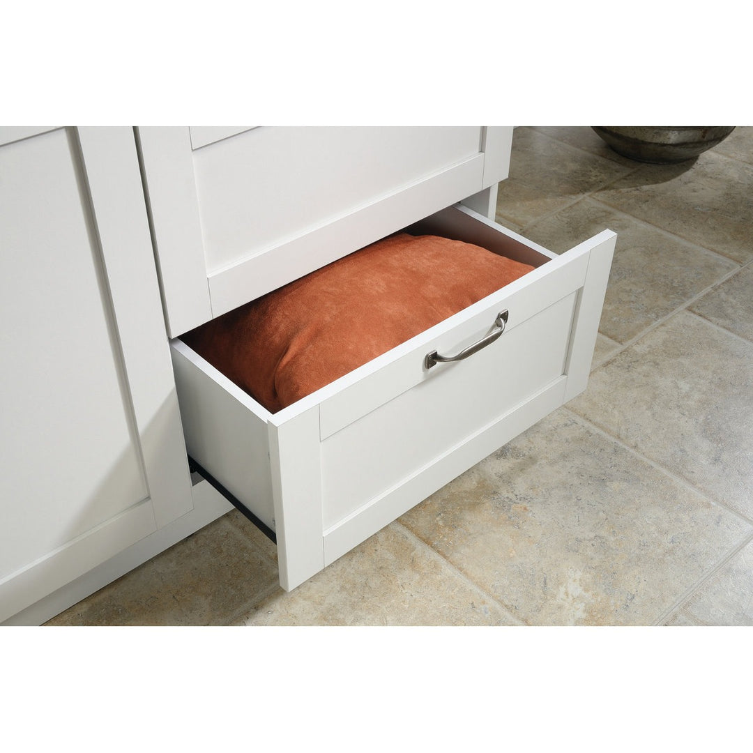 White cabinet with an open drawer containing a brown cushion on a tiled floor.