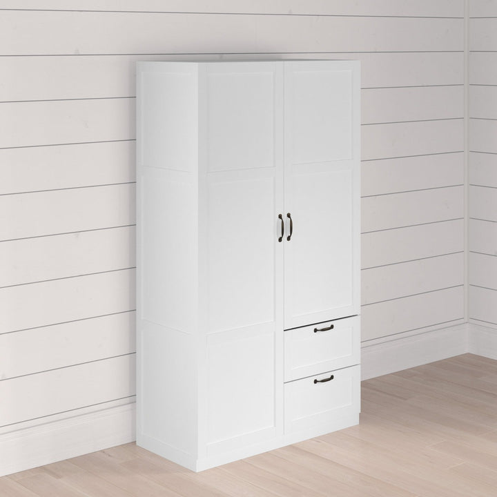 White wardrobe with black handles against a white paneled wall.