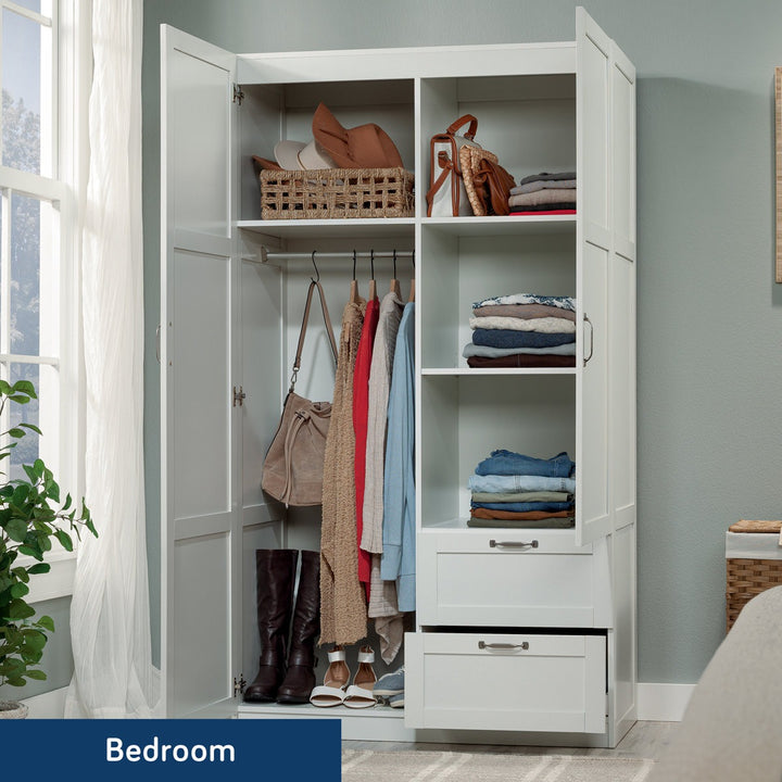 White 2-door wardrobe with clothes and bags in a bedroom setting