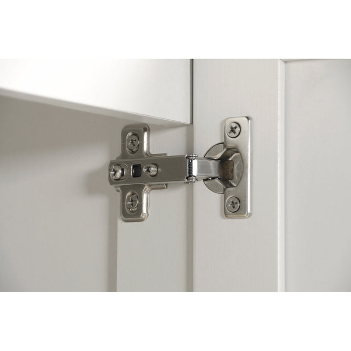 Close-up of a cabinet hinge on a white door 