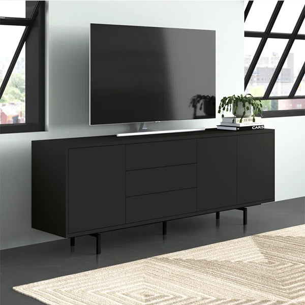 A black Union sideboard and cabinet with three doors and drawers, featuring a metal frame and soft-close mechanism, placed in a room with a large television and a rug on the floor.