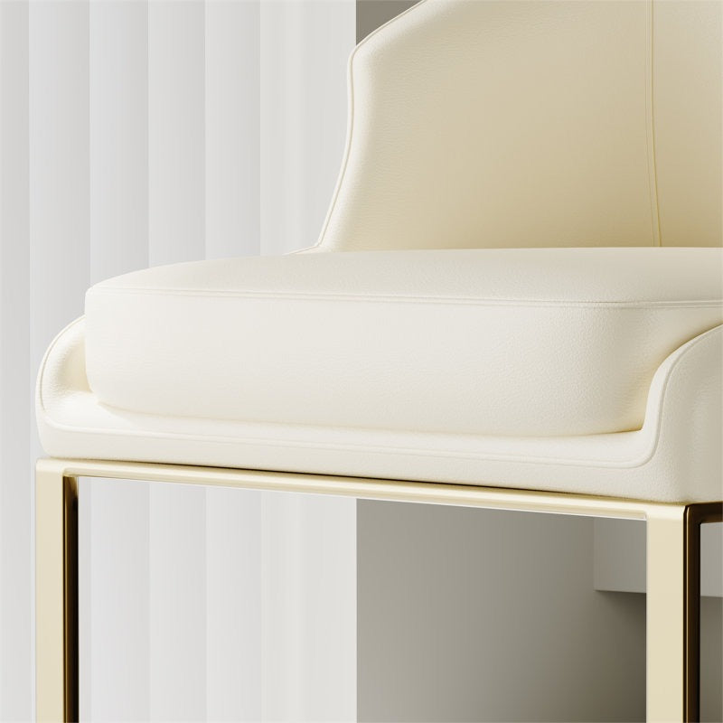 Close-up of a white chair with gold legs in a minimalistic setting.