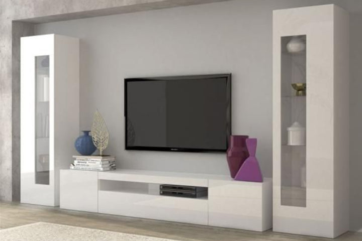 A white matte TV unit set with a flat-screen TV, magazines, and decorative items on top in a modern living room setting.