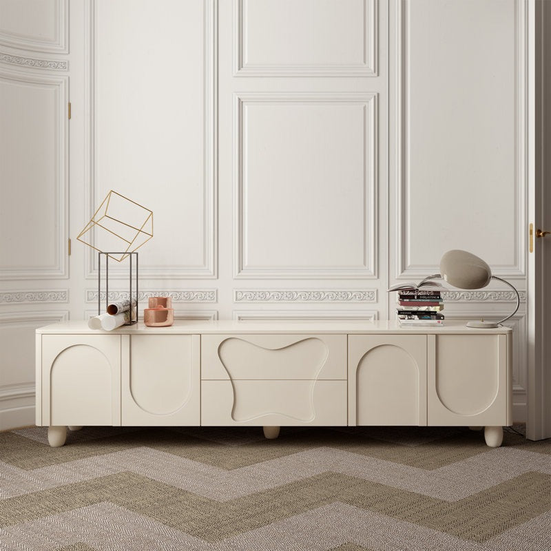 A white, large DIZI TV stand with a unique 3D carved design, featuring two drawers and four open shutters for storage, set against a room with white panelled walls.