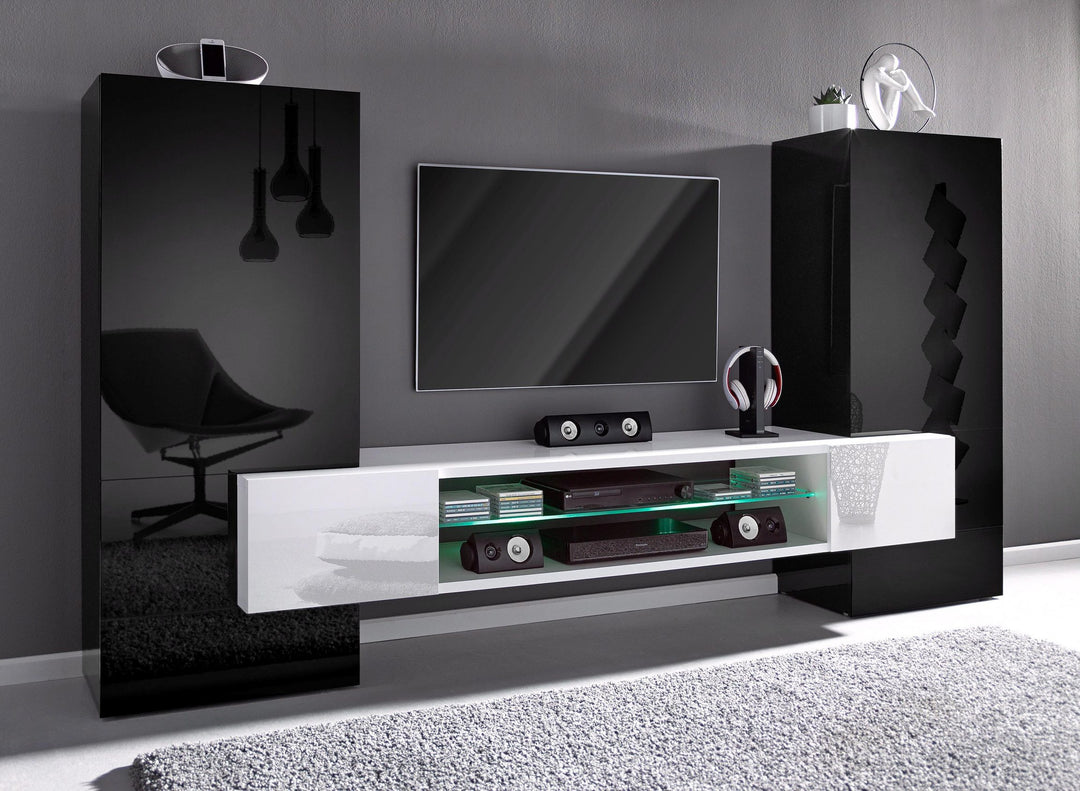 A modern TV unit set with a white glossy laminate finish on the upper part and a black matte finish on the lower part, featuring a flat-screen TV, storage cabinets, and glass shelves.