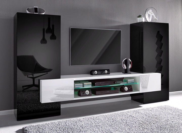 A modern TV unit set with a white glossy laminate finish on the upper part and a black matte finish on the lower part, featuring a flat-screen TV, storage cabinets, and glass shelves.