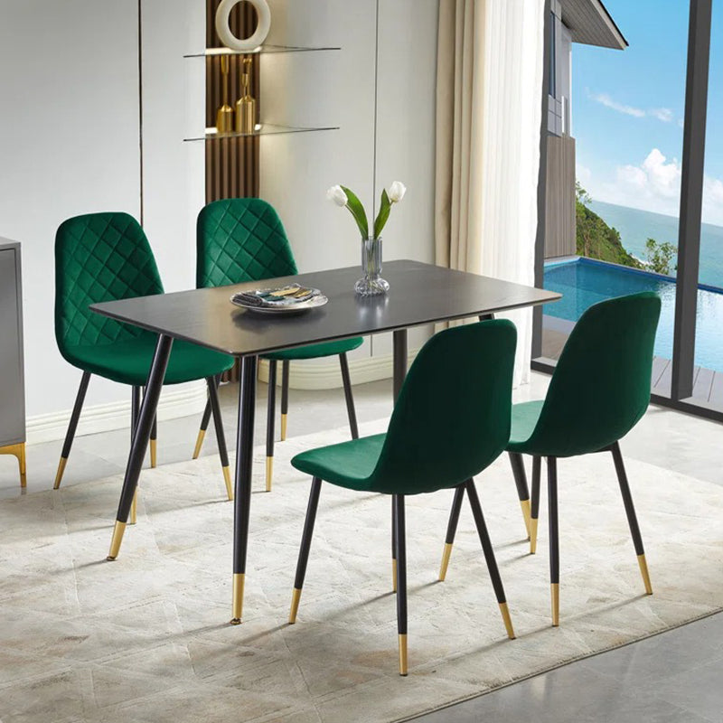 A set of four green fabric upholstered dining chairs with black metal legs and a rectangular dining table with a modern design, all set in a bright room with a view of a pool.