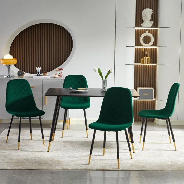 Modern green dining chairs with black and gold accent legs and a sleek black dining table 