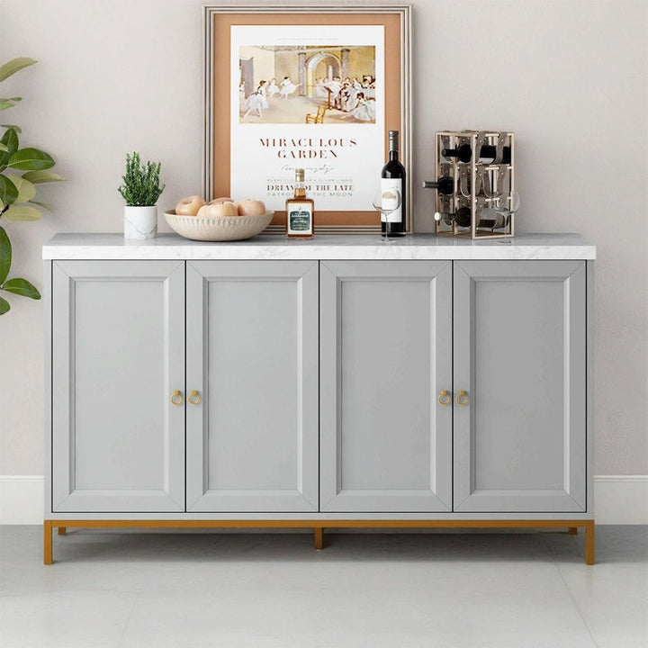 A large grey Fanto sideboard with a gold metal base, featuring four shutter storage units, placed against a white wall with decorative items on top.
