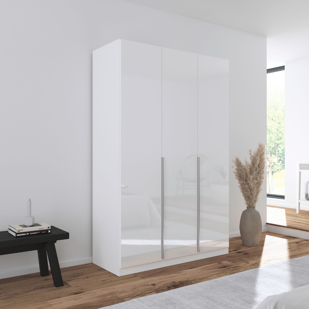A white gloss 3-door wardrobe with a minimalist design, featuring six shelves and two hanging rods, positioned in a bright bedroom setting.