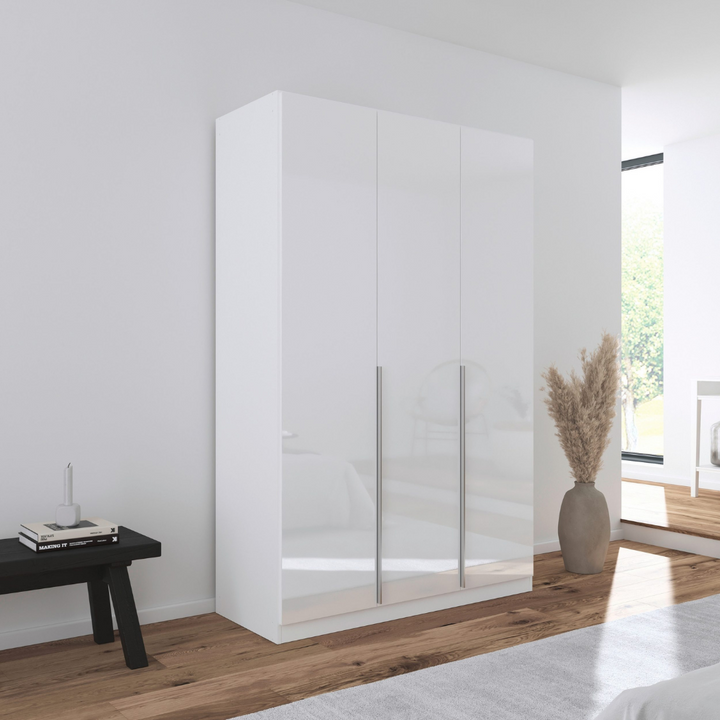 A white gloss 3-door wardrobe with a minimalist design, featuring six shelves and two hanging rods, positioned in a bright bedroom setting.