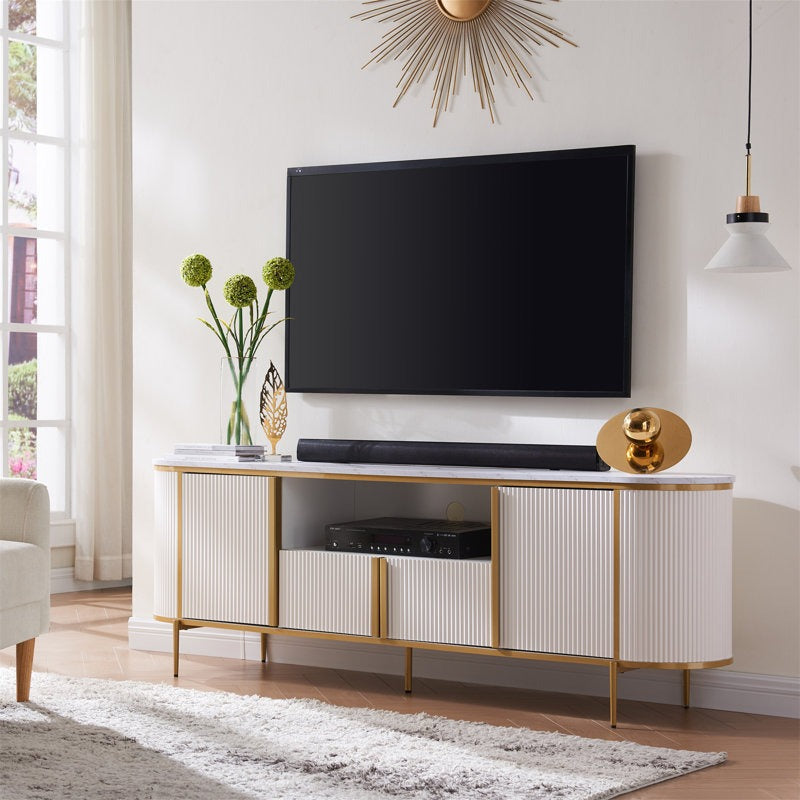 A modern white TV stand with gold accents, featuring a curved design and mounted with a flat-screen television above it, placed in a room with minimalist decor.
