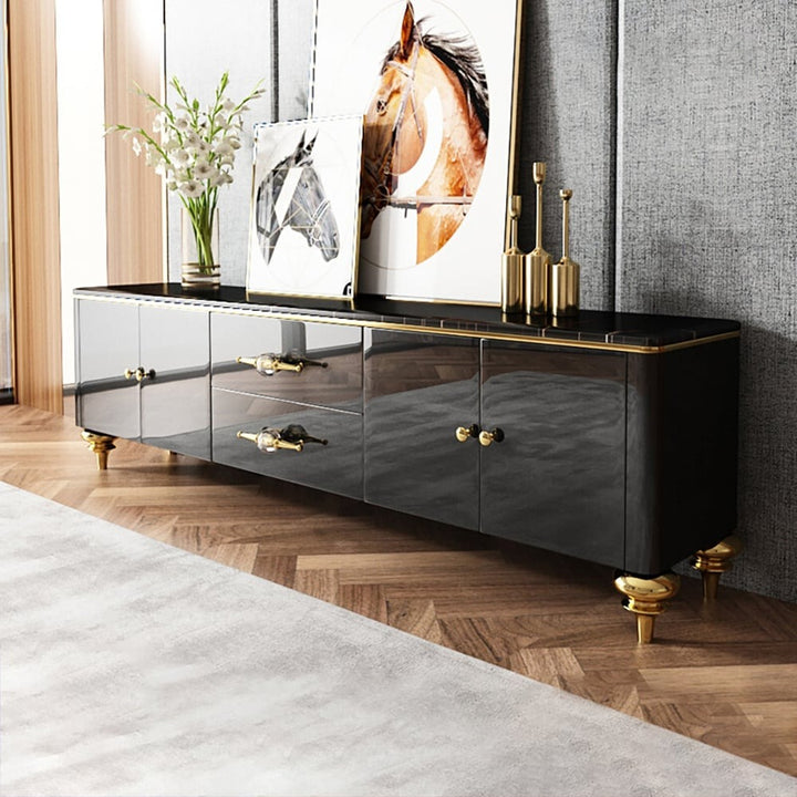 Modern black TV unit with marble top, gold finish legs and handles in a living room 