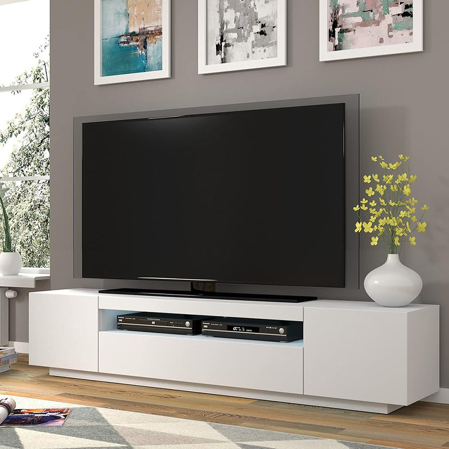 A modern white matte TV stand with three soft-close cabinets and an open shelf, displayed in a living room setting with a flat-screen TV on top.