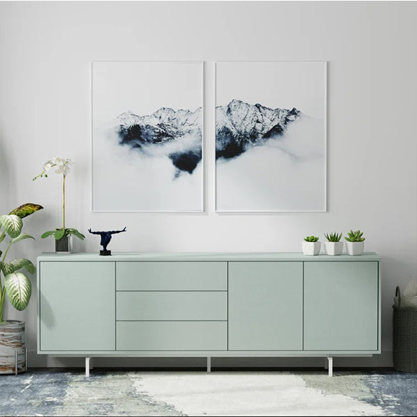 A pale green Union sideboard and cabinet with metal legs, featuring a simple design with three doors and drawers, displayed in a room setting with decorative items and a plant beside it.