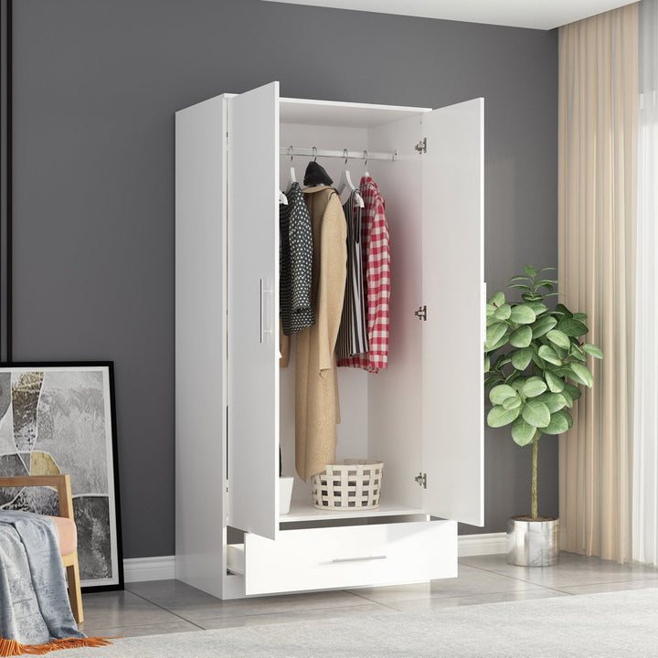 White 2-door wardrobe with clothes inside in a room with a plant and wall art.
