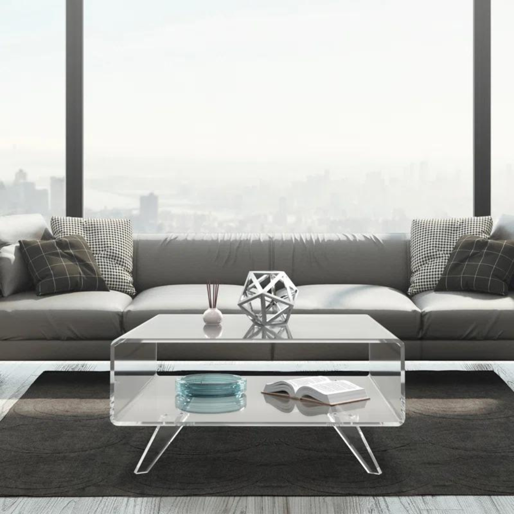 A clear acrylic center table placed on grey rug with light grey sofa