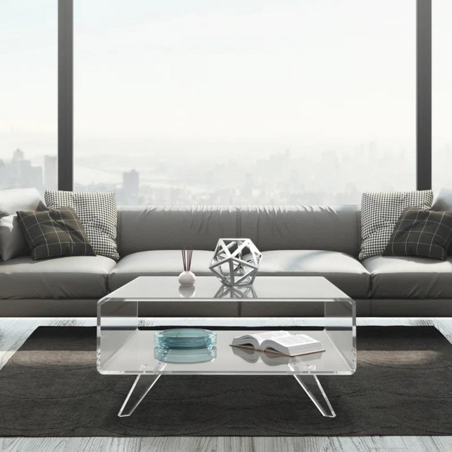 A clear acrylic center table placed on grey rug with light grey sofa