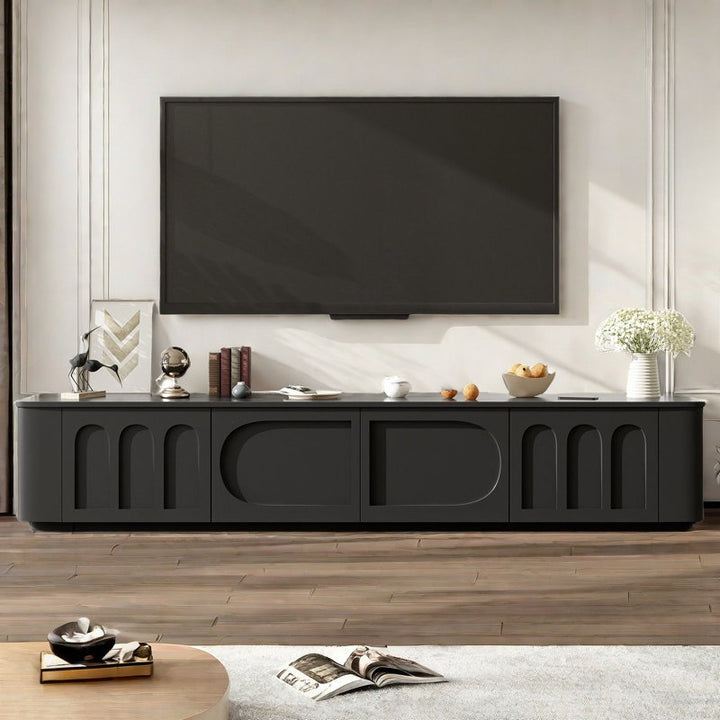 A large black TV stand with arched doors and a sleek silhouette, featuring a flat-screen TV on top and a few decorative items.