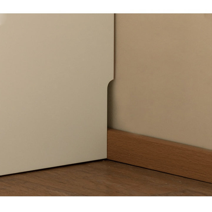 Close-up of a corner where beige wall meets wooden baseboard.