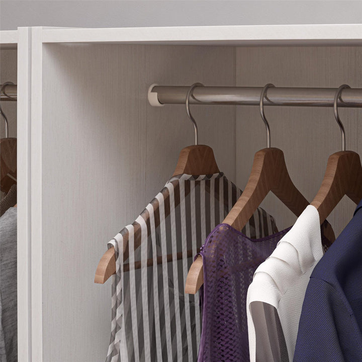 Clothing items on wooden hangers inside a white wardrobe.
