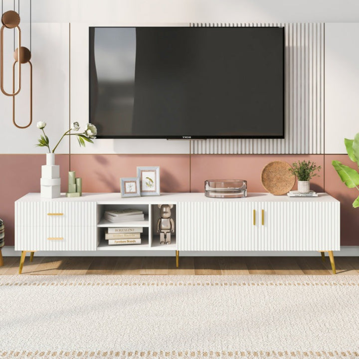 A modern white TV stand with hidden compartments and gold accents, with a flat-screen TV mounted on the wall above it, set against a minimalist decor background.