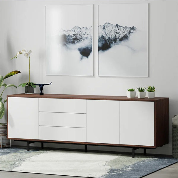 modern white sideboard with walnut brown legs, featuring three doors and drawers, displayed in a room with a mountain-inspired artwork above