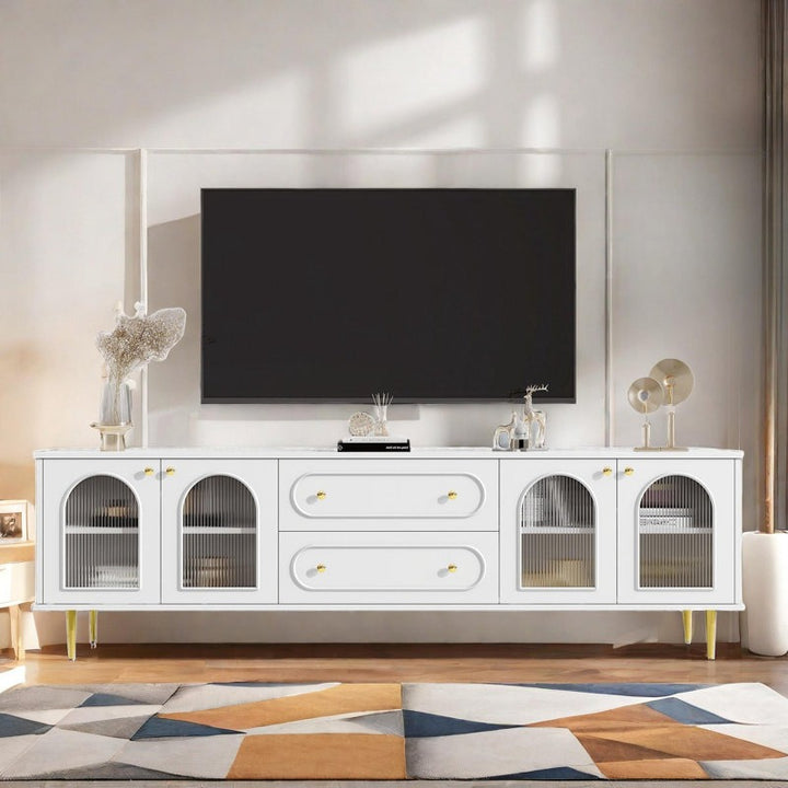 A sleek white Broho TV stand with arched glass doors and golden knobs, featuring a high-gloss PU paint finish and metal legs, placed in a room with a flat-screen TV on top.