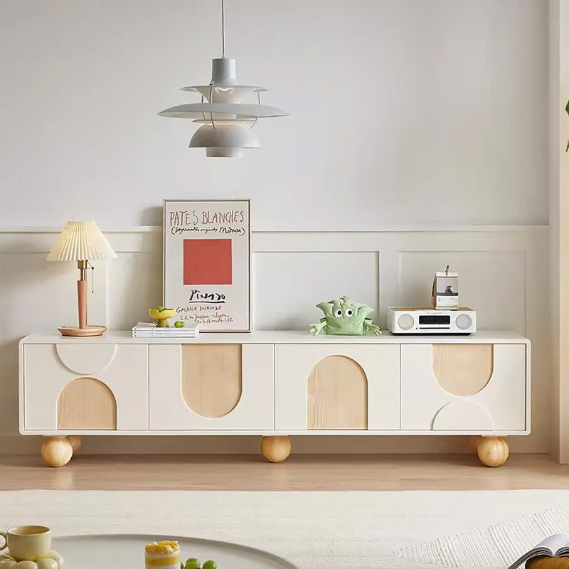 A white Brunzy TV stand with solid wood ball legs, featuring cut-outs in a different wood tone and spherical decorations on top.