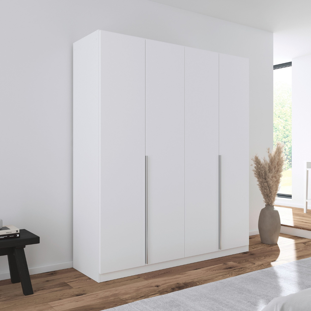 A matte white 4-door wardrobe with handle-less design, placed in a room with a decorative vase to the side.