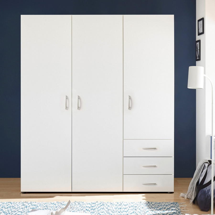 A modern white 3-door wardrobe with drawers and shelves, placed against a blue wall with a white handle on the door.
