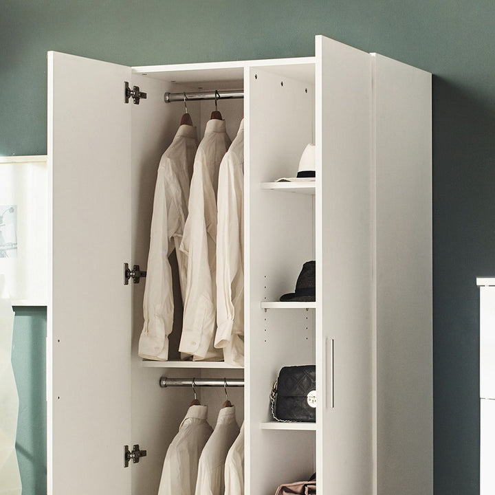 White 2-door wardrobe with clothes and bags inside against a gray wall